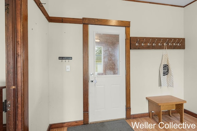 doorway to outside with baseboards, crown molding, and wood finished floors
