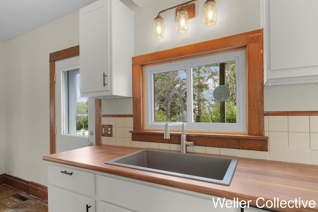 kitchen with a sink, white cabinetry, and tasteful backsplash