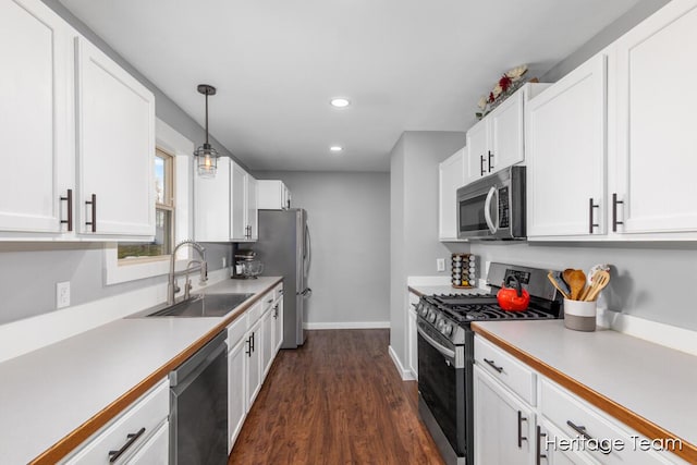 kitchen with baseboards, dark wood-style floors, white cabinetry, a sink, and stainless steel appliances