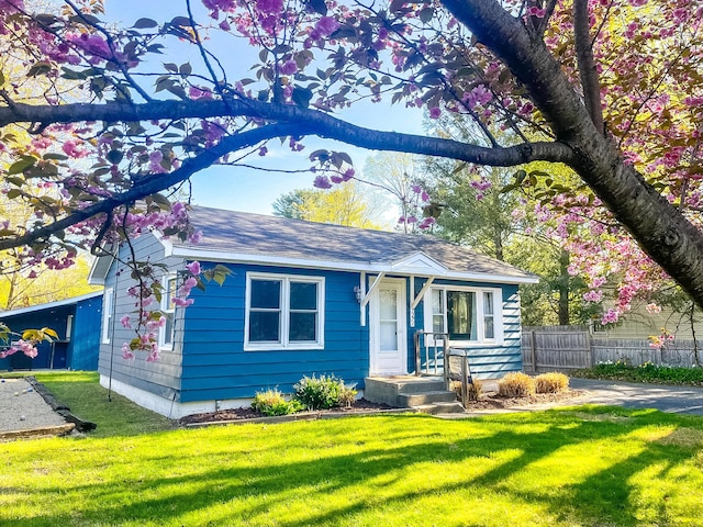 view of front facade with roof with shingles, fence, and a front yard