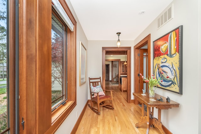 hall featuring baseboards, visible vents, and light wood-type flooring