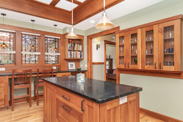 bar featuring baseboards, hanging light fixtures, and light wood-style flooring