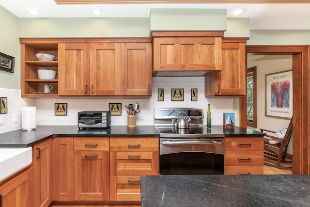 kitchen with stainless steel electric range oven, backsplash, brown cabinetry, and a toaster