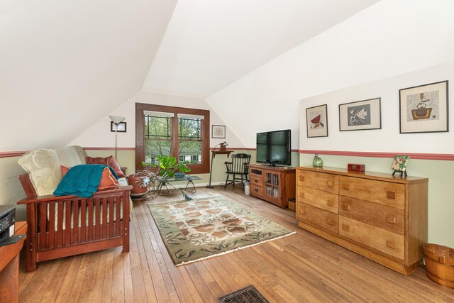 bedroom with wood-type flooring, visible vents, and lofted ceiling