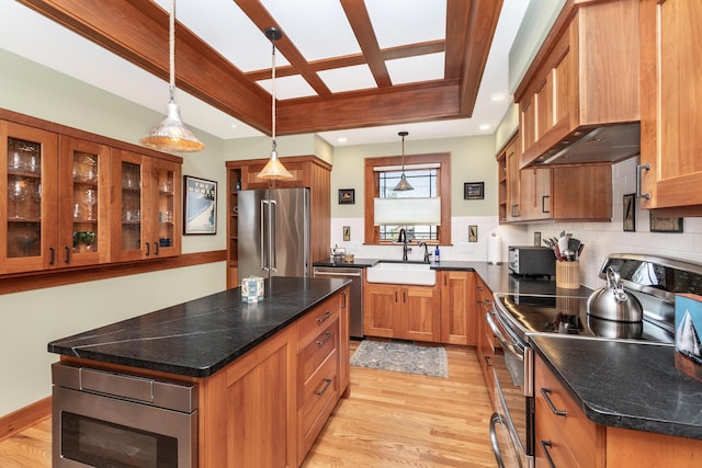 kitchen featuring brown cabinetry, a kitchen island, custom range hood, a sink, and stainless steel appliances