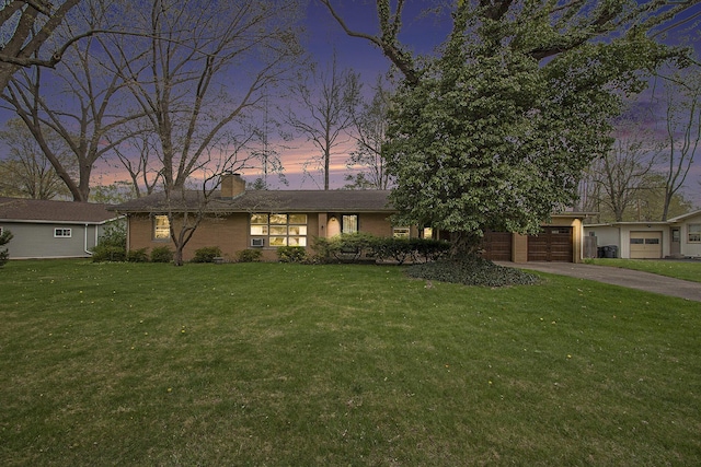 view of front facade with an attached garage, a chimney, a front yard, and aphalt driveway