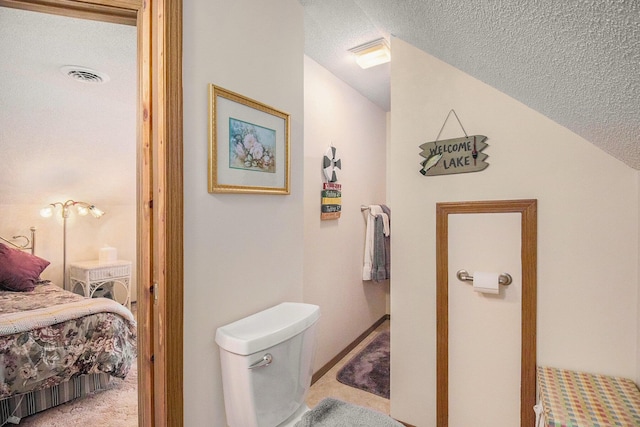 ensuite bathroom featuring visible vents, connected bathroom, a textured ceiling, and toilet