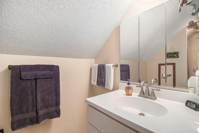 bathroom featuring vanity, a textured ceiling, and vaulted ceiling