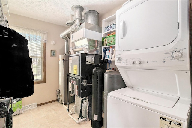 laundry room featuring gas water heater, laundry area, stacked washer and dryer, visible vents, and baseboards