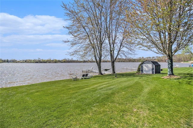 view of yard with an outbuilding, a water view, and a shed