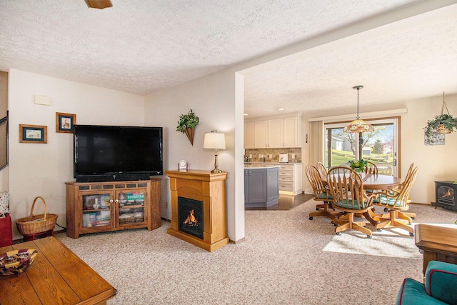 living area with a textured ceiling, a lit fireplace, and carpet