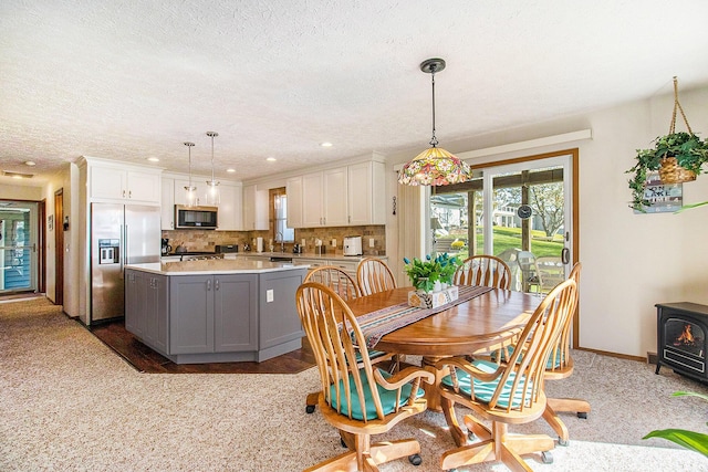 dining space featuring recessed lighting, a textured ceiling, baseboards, and a wood stove