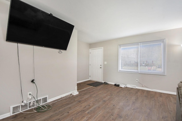 unfurnished living room with baseboards and wood finished floors