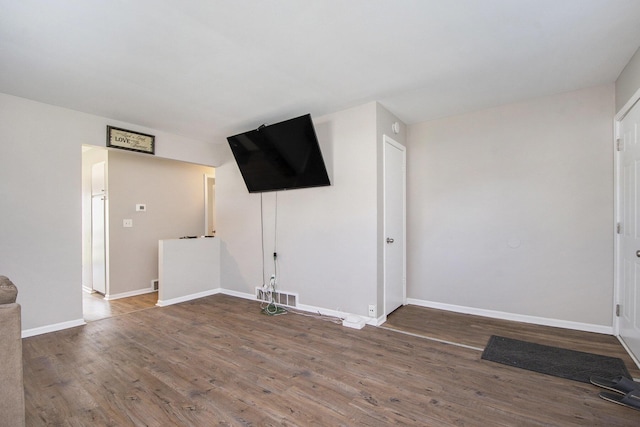unfurnished living room featuring baseboards, wood finished floors, and visible vents