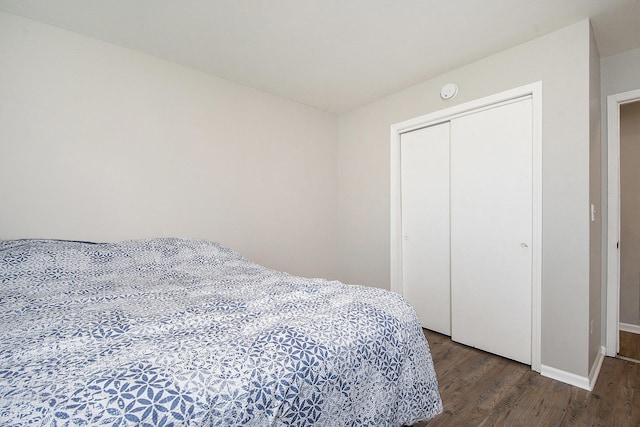 bedroom with baseboards, wood finished floors, and a closet