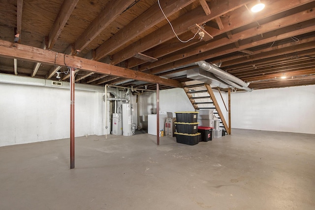 unfinished below grade area featuring stairs, separate washer and dryer, visible vents, and water heater