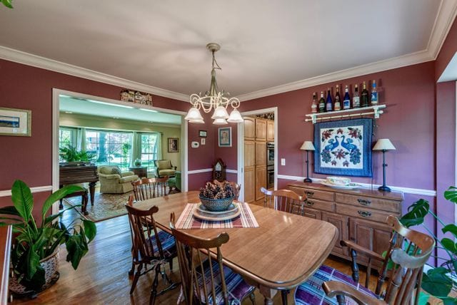 dining room featuring crown molding, an inviting chandelier, and wood finished floors