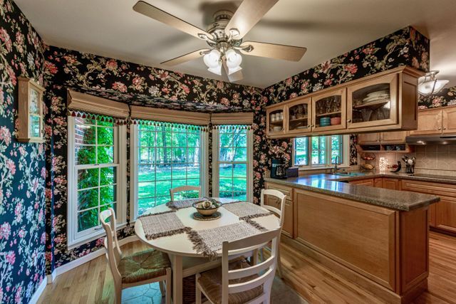 dining space with light wood finished floors, a ceiling fan, and wallpapered walls