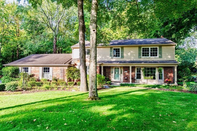 traditional-style home featuring brick siding and a front lawn