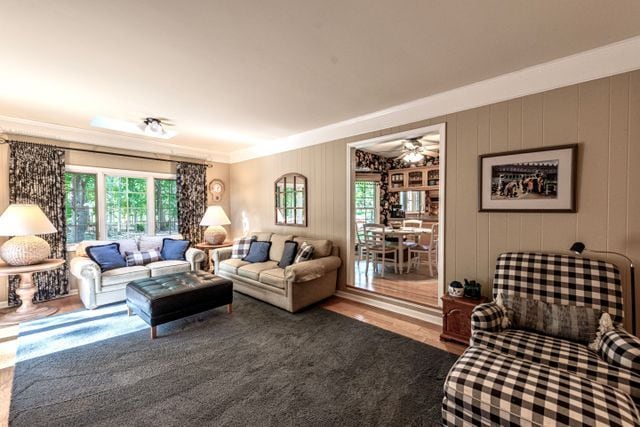 living area with plenty of natural light, ornamental molding, a ceiling fan, and wood finished floors