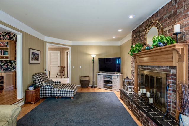 living area with ornamental molding, a brick fireplace, and wood finished floors