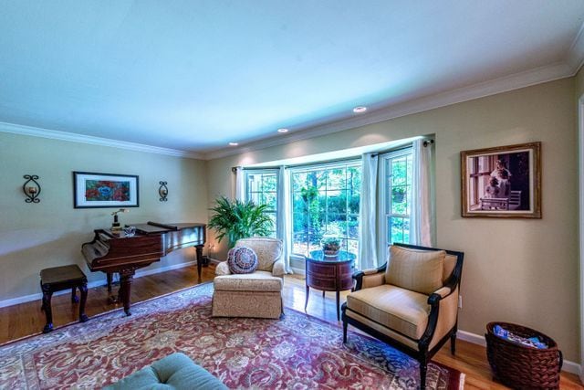 living area with crown molding, baseboards, and wood finished floors
