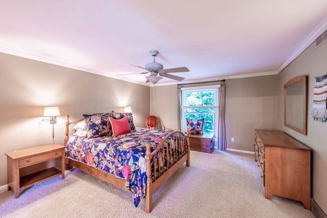 bedroom with light colored carpet, ornamental molding, baseboards, and a ceiling fan