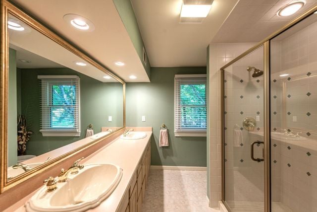 bathroom with double vanity, a sink, and a stall shower