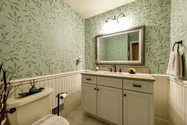 bathroom featuring visible vents, wainscoting, toilet, and wallpapered walls