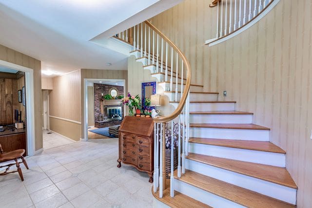 stairs with tile patterned floors, wooden walls, and a fireplace