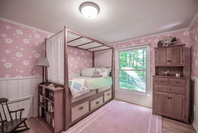 bedroom featuring light wood-type flooring, wainscoting, and wallpapered walls