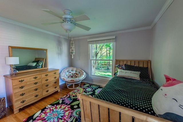 bedroom with crown molding, baseboards, and light wood-style flooring