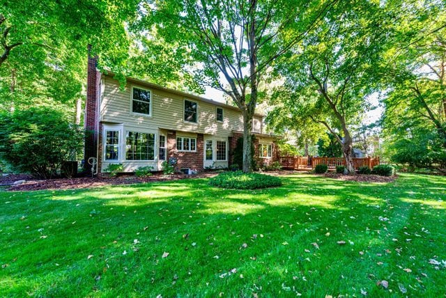 rear view of house featuring fence, a yard, and a chimney