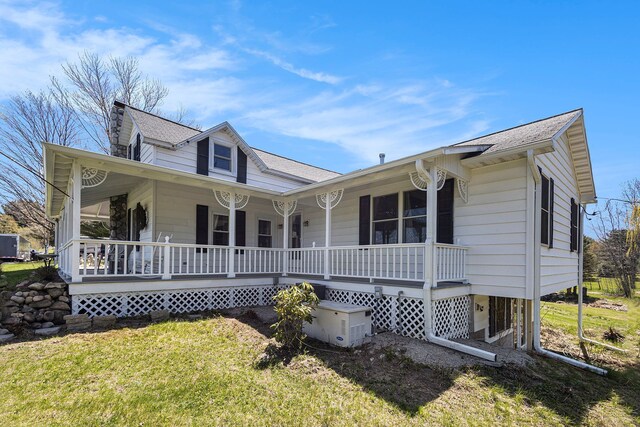 3121 Grace Rd, Frankfort, MI 49635 - view of front facade with covered porch, a front yard, and a shingled roof