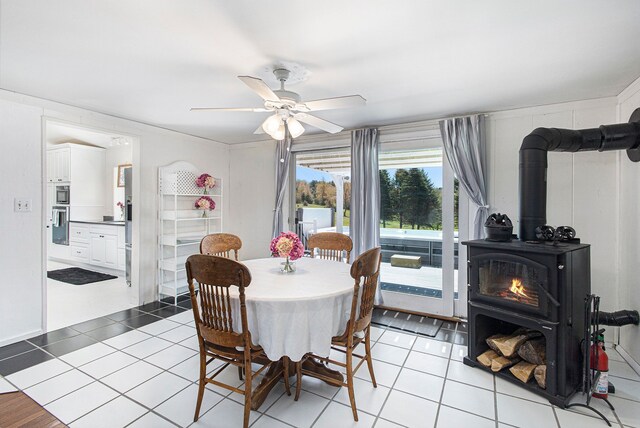 3121 Grace Rd, Frankfort, MI 49635 - dining room featuring a wood stove, a ceiling fan, and light tile patterned flooring