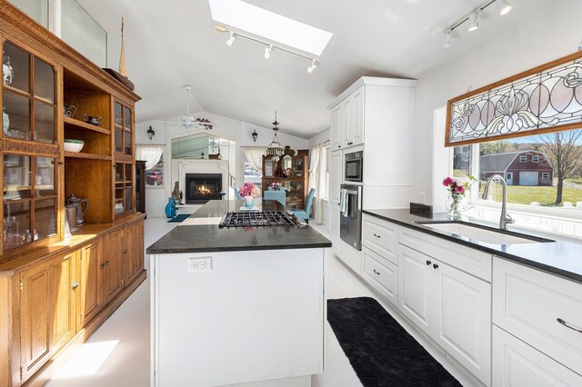 3121 Grace Rd, Frankfort, MI 49635 - kitchen with rail lighting, a sink, gas cooktop, a lit fireplace, and lofted ceiling