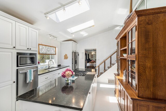 3121 Grace Rd, Frankfort, MI 49635 - kitchen featuring rail lighting, appliances with stainless steel finishes, a sink, a skylight, and a center island