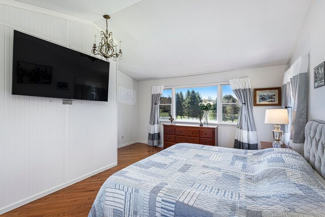 3121 Grace Rd, Frankfort, MI 49635 - bedroom with dark wood-type flooring, lofted ceiling, a chandelier, and baseboards