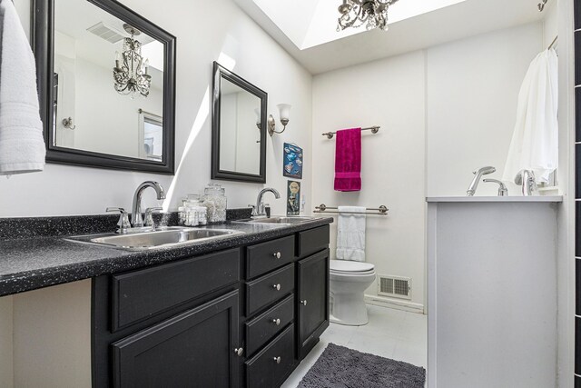3121 Grace Rd, Frankfort, MI 49635 - full bath featuring double vanity, toilet, tile patterned floors, and a skylight