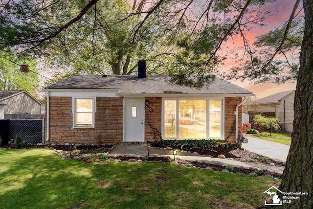 view of front of property with fence, a chimney, a yard, and stone siding