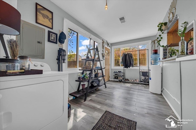 washroom with electric panel, laundry area, washer / clothes dryer, visible vents, and light wood-style flooring