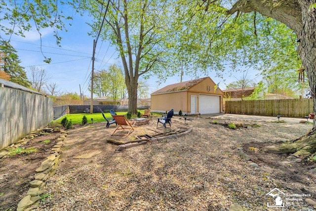 view of yard with a detached garage, a fire pit, an outbuilding, and a fenced backyard