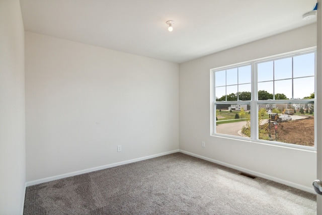 carpeted empty room featuring baseboards and visible vents