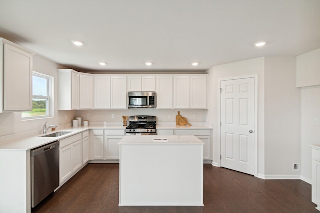 kitchen with appliances with stainless steel finishes, dark wood-style floors, a sink, and a center island
