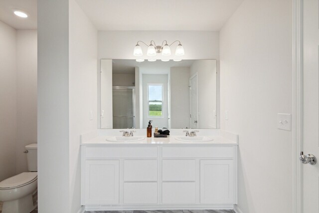 full bath with double vanity, a sink, toilet, and a shower stall