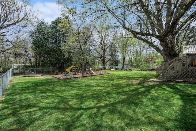 view of yard with a fenced backyard, a playground, and stairway