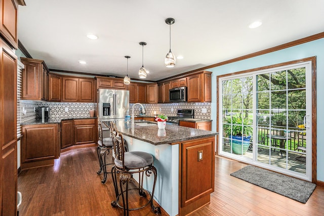 kitchen featuring crown molding, a sink, stainless steel appliances, decorative backsplash, and dark wood-style floors