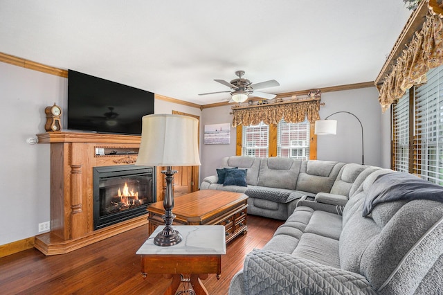 living room with a glass covered fireplace, ceiling fan, ornamental molding, and wood finished floors