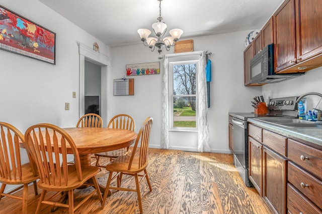 dining space featuring light wood-type flooring, baseboards, and an inviting chandelier