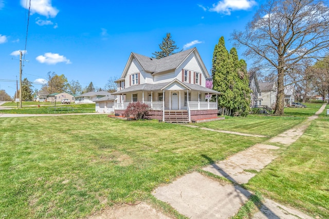 view of front facade featuring a shingled roof, covered porch, and a front yard